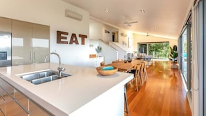 Una cocina moderna con una isla grande, un comedor con mobiliario de madera y vistas al exterior.
