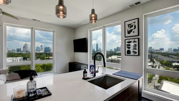 A modern kitchen with a large window, a built-in sink, and a city view.