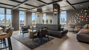 A modern living room with a fireplace, seating area, and large windows offering city views.