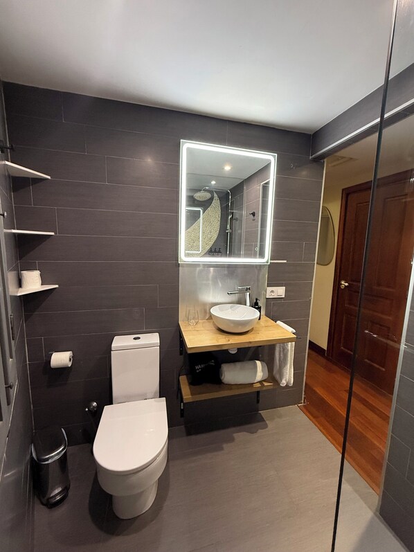 Un baño moderno con inodoro, lavabo y espejo.
