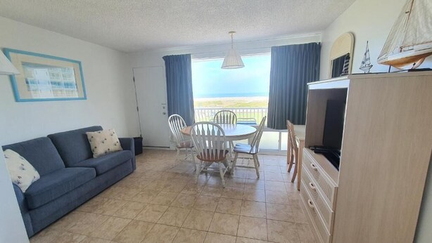 Una sala de estar con sofá, mesa de comedor, sillas y un mueble para televisión.