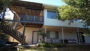 Une maison à deux étages dotée d’un balcon, d’une porte d’entrée et d’un petit espace porche aménagé avec du mobilier d’extérieur.