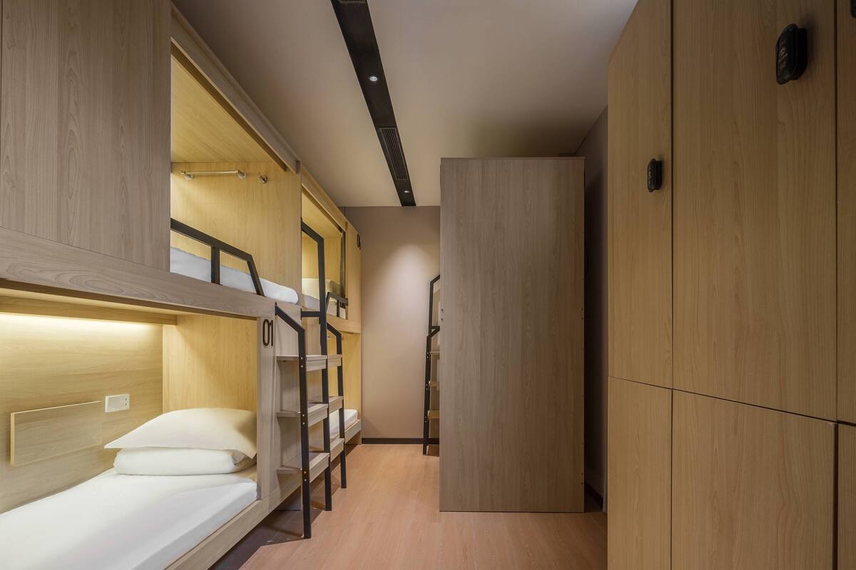 Une petite chambre avec des lits superposés, une armoire et un petit bureau.