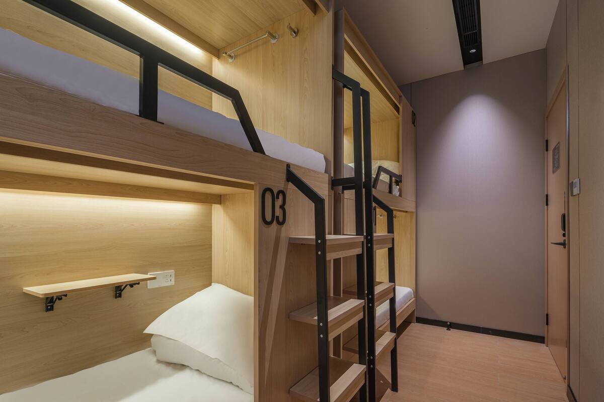 Une chambre avec un lit superposé en bois, une étagère et un escalier.