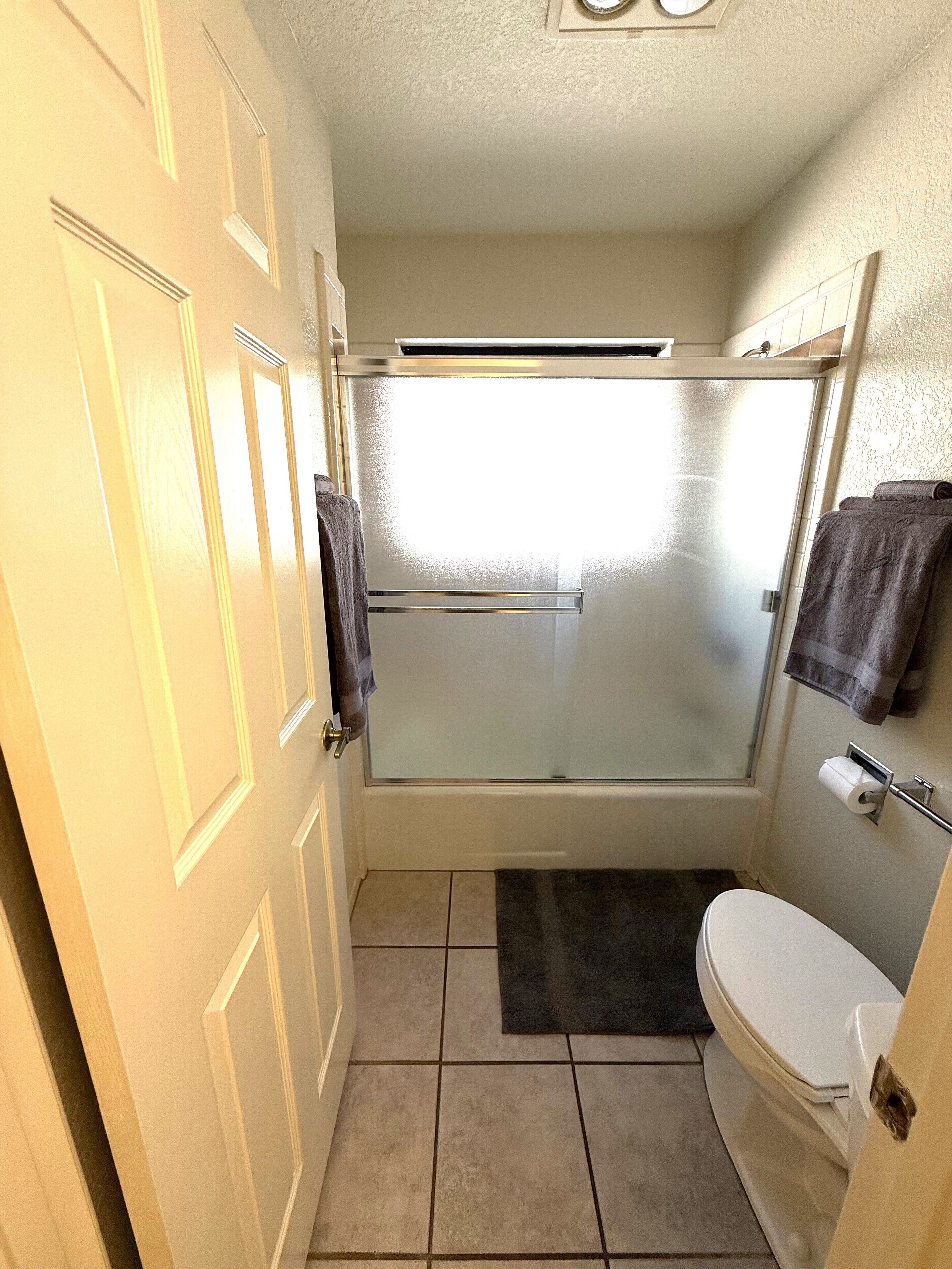 Une petite salle de bain comprenant une douche, des toilettes et un porte-serviettes.