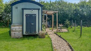 A small, single-story shed with a door and a covered porch. - Daisy Shepherd's Hut, North Molton (North Molton)
