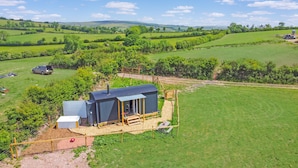 Une propriété rurale comprenant un petit abri en métal, une terrasse en bois et un jardin clos.