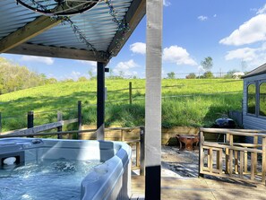 A hot tub, wooden deck, and a view of a grassy field. - Hedgehogs Lodge, South Molton (South Molton)