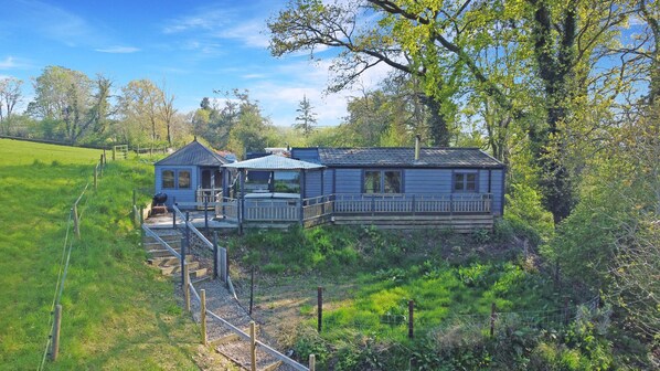 Une maison à deux étages avec un porche, une petite terrasse et une cour clôturée.