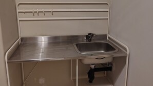 Una pequeña cocina americana con encimera de acero inoxidable, un lavabo y un grifo.