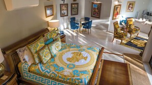 Een ruime slaapkamer met een groot bed, een zithoek met stoelen en een eettafel.