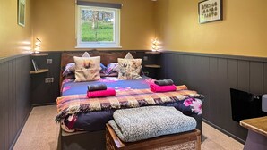 Ein Schlafzimmer mit einem Bett, Nachttischen, einem Fenster und einem an der Wand befestigten Fernseher.