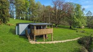 A wooden cabin with a balcony, a small shed, and a gravel path. - Robins Nest Lodge, South Molton (South Molton)