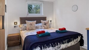 Une chambre à coucher avec un lit, des tables de chevet, une fenêtre et une horloge murale.