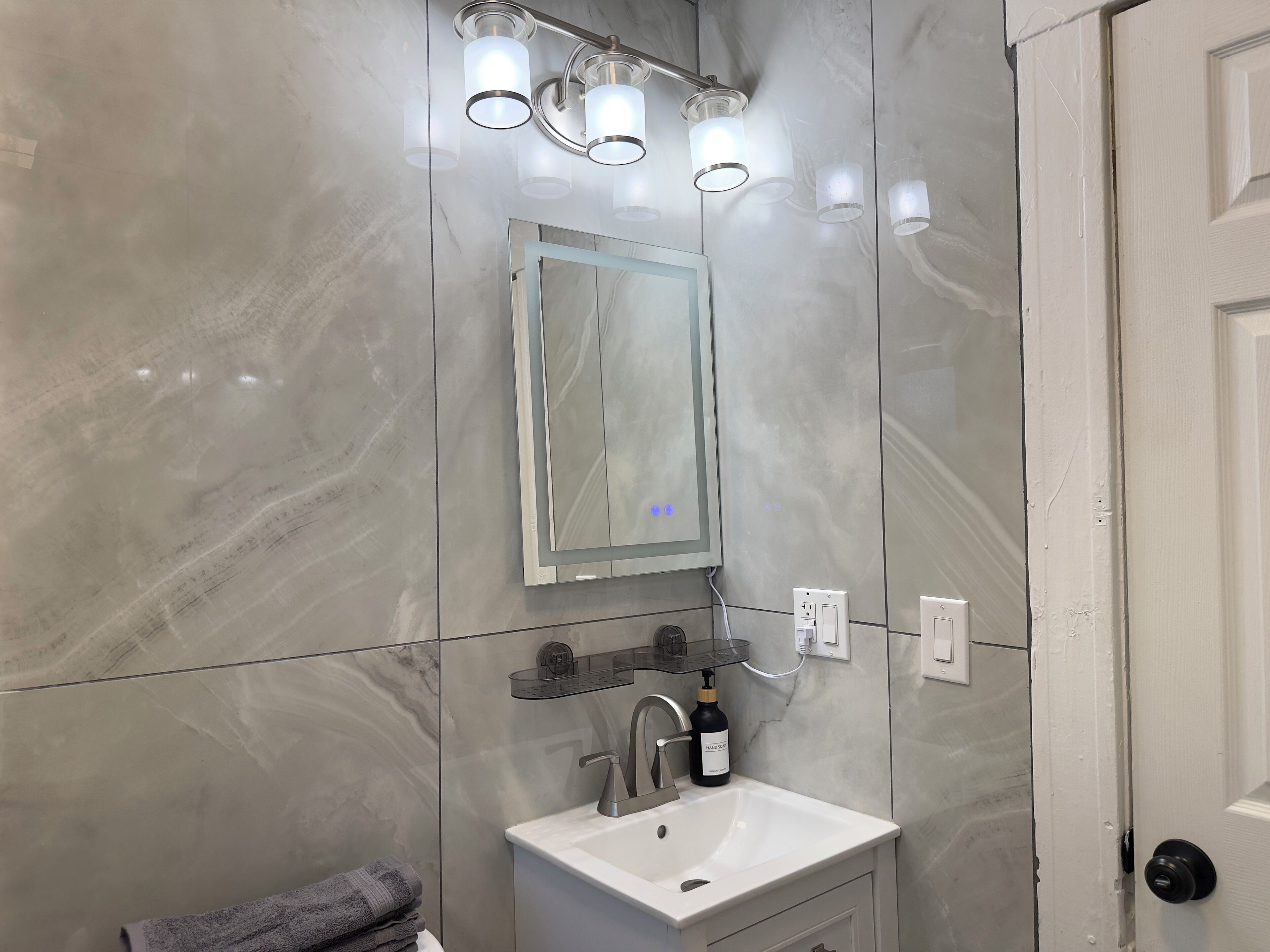 A bathroom with a white sink, a mirror, and three wall-mounted lights.
