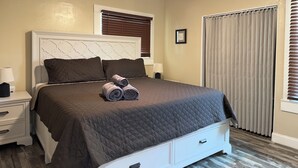 A neatly made bed with a quilted brown bedspread, a ceiling fan, and a window with blinds. - Sequoia Escape 3BR Home w/ King Bed & In-Unit Laundry (Visalia)