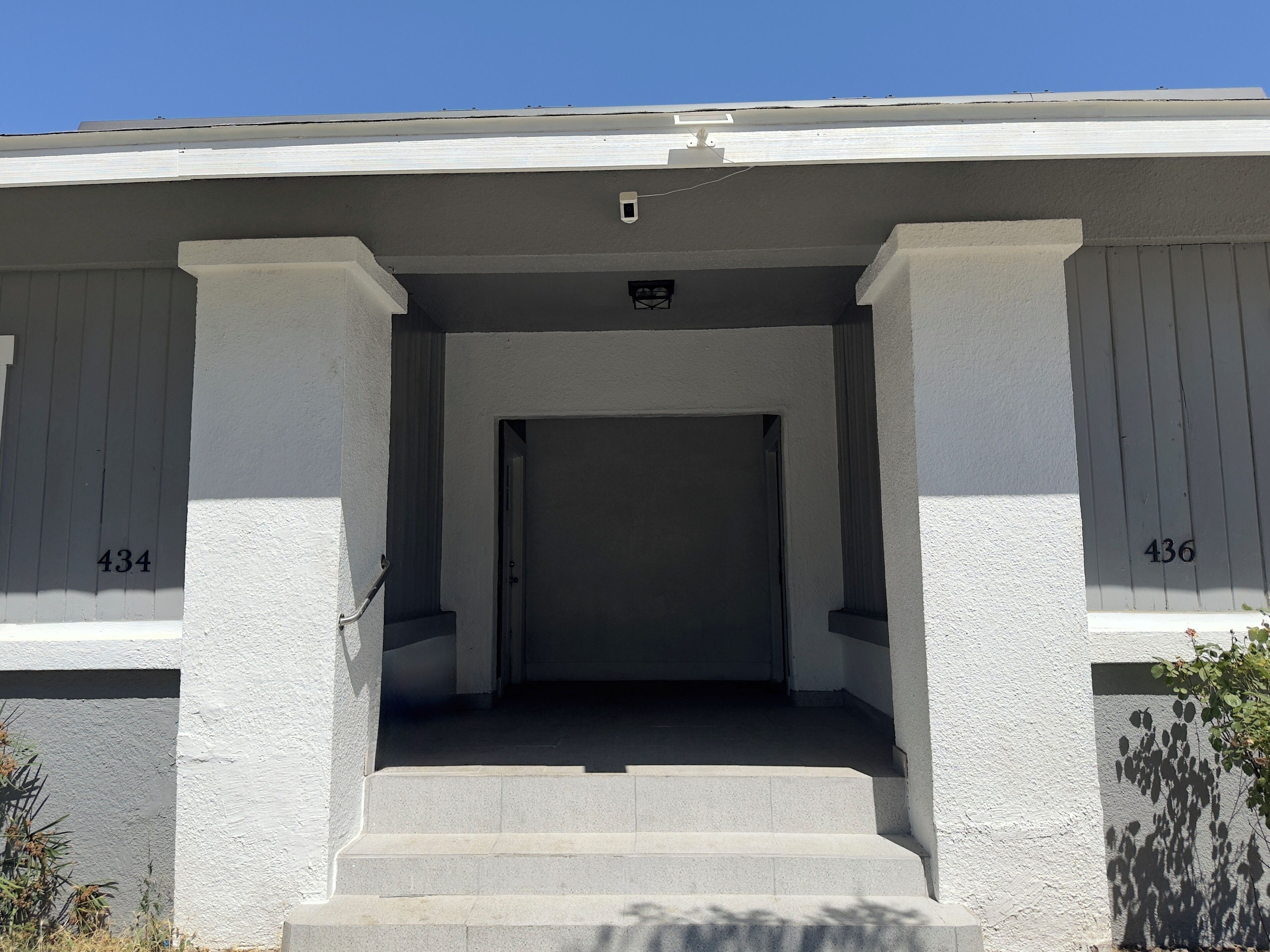 A building entrance with a set of steps leading to a door, flanked by two columns.