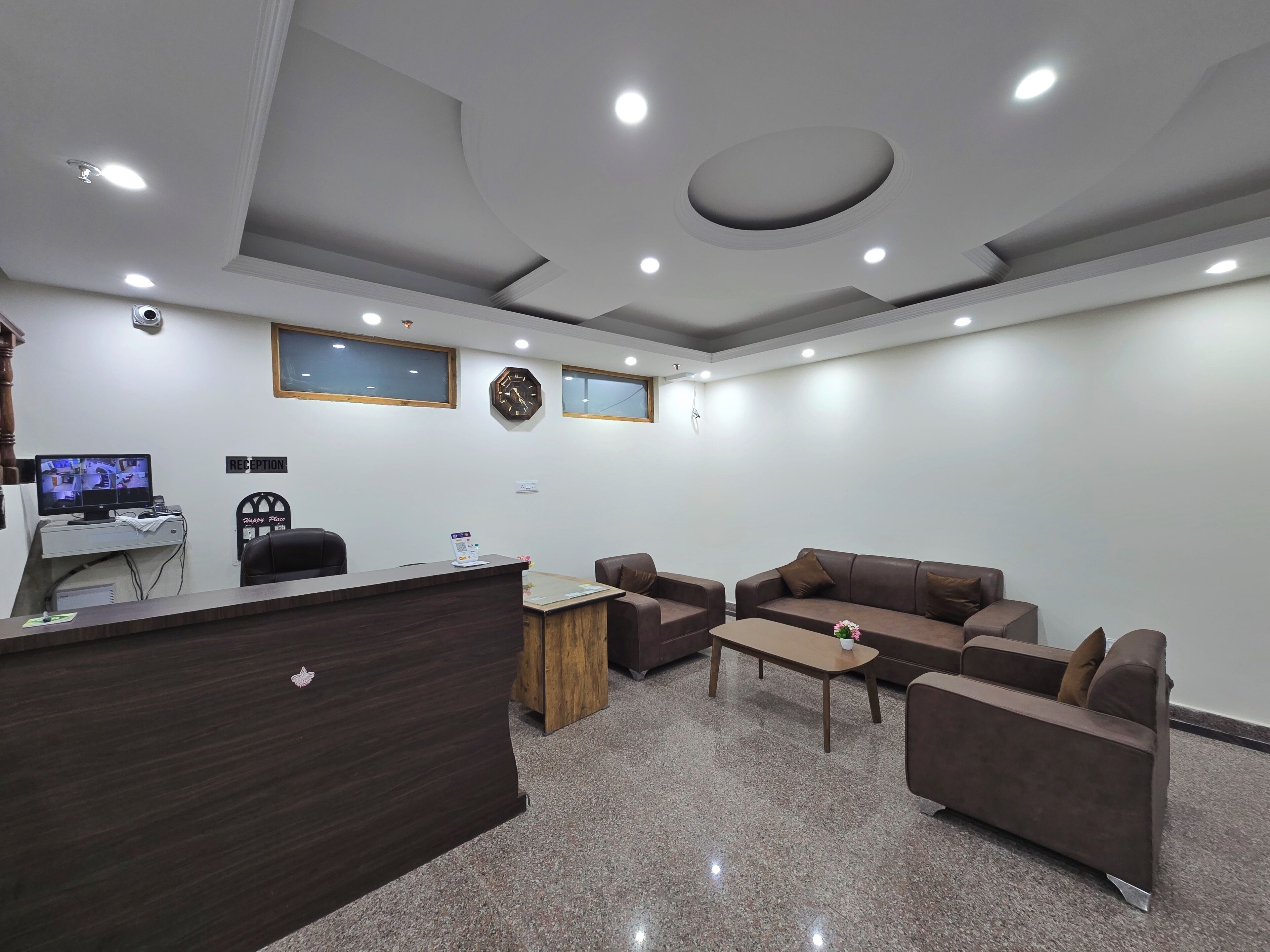 A reception area with a desk, chairs, a clock, and a reception sign.