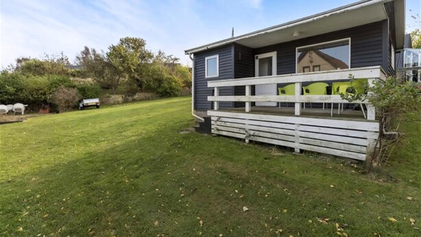 A single-story house with a porch, a small deck, and a grassy yard.