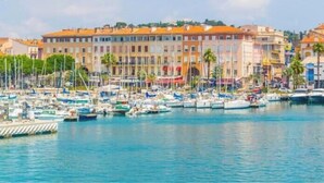 Uma marina com barcos atracados, um edifício à beira-mar e céu claro.
