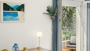 Quarto moderno com escrivaninha de madeira, luminária globo e pintura emoldurada de paisagem.