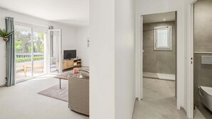 Uma sala de estar moderna com sofá, televisão e uma porta de vidro deslizante para área externa.