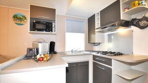 A compact kitchen with a microwave, toaster, and sink. - Mobile Home proche mer piscine (Narbonne Plage)