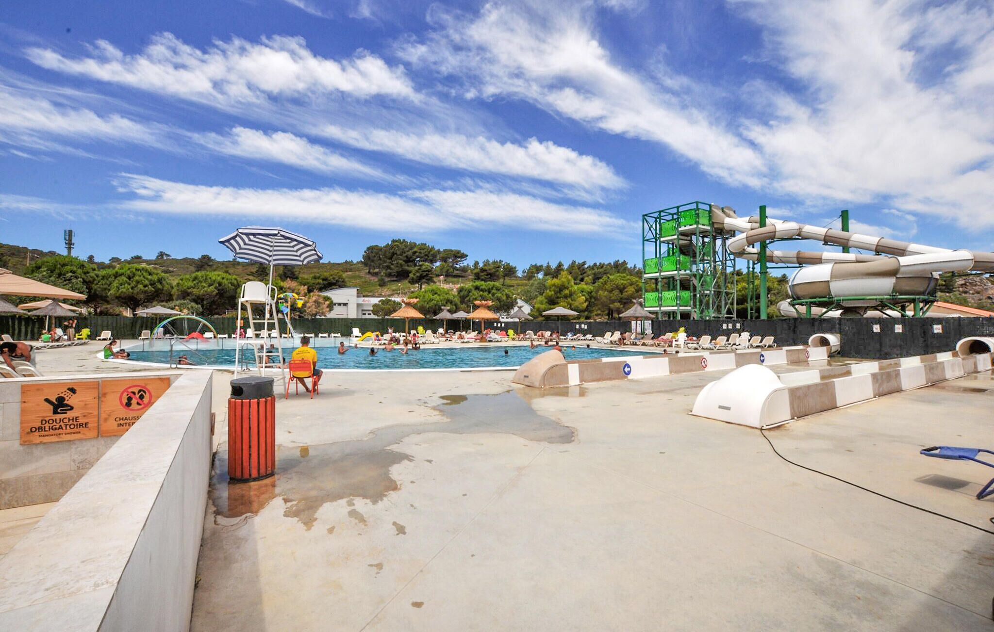 A pool area with a water slide, lounge chairs, and a lifeguard stand.