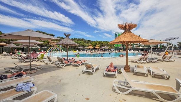A poolside area with lounge chairs, umbrellas, and a water slide. - Mobile Home proche mer piscine (Narbonne Plage)