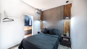 A modern bedroom with a large bed, a wooden accent wall, and a hanging light fixture.