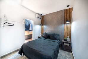 Une chambre moderne avec un grand lit, un mur d’accent en bois et un luminaire suspendu.
