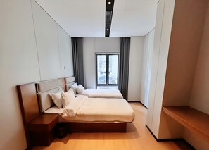 Un dormitori modern amb un llit gran, una nitzeta i una finestra amb cortines.