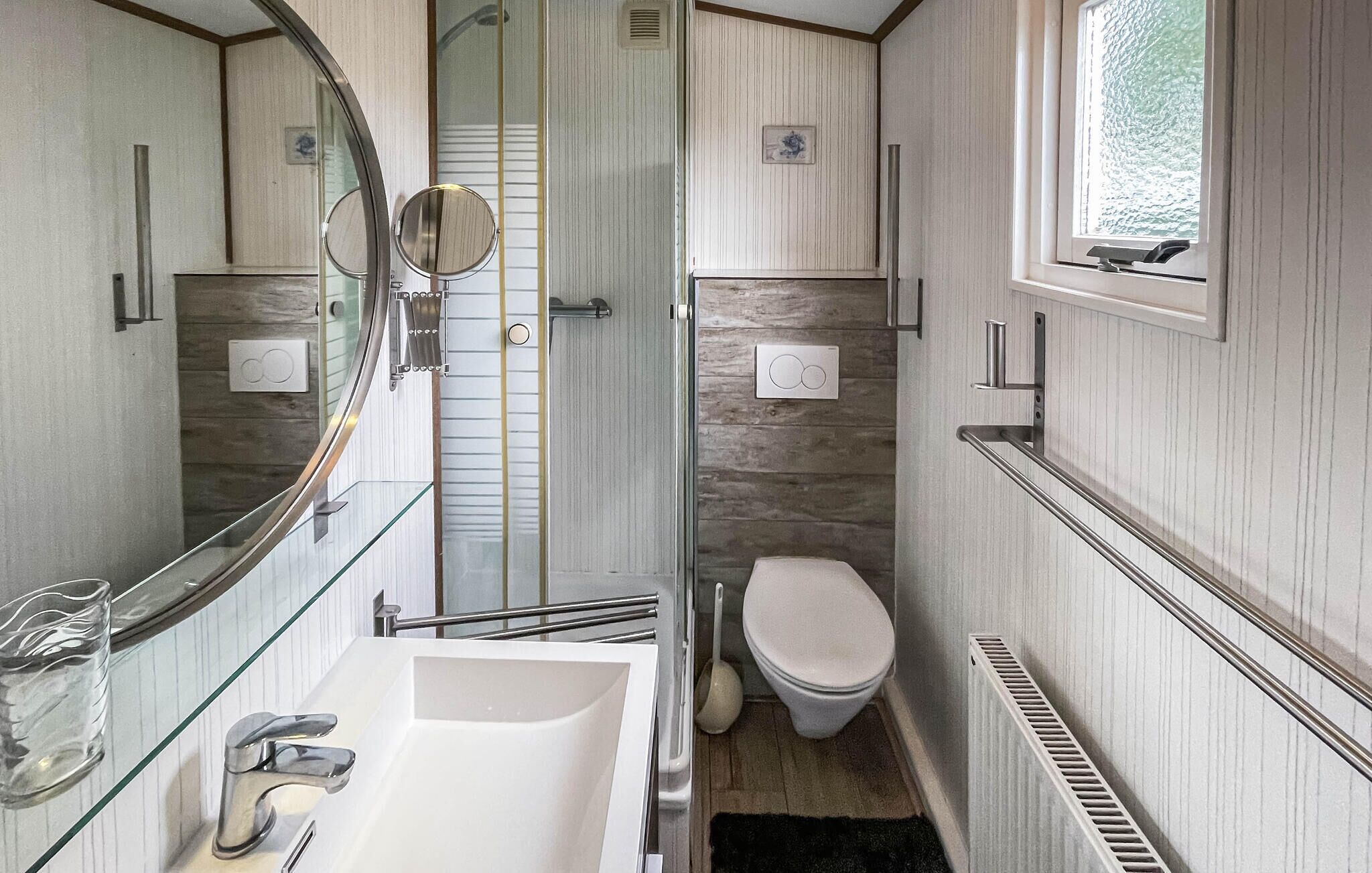 A compact bathroom with a glass shower enclosure, a white sink, and a toilet.