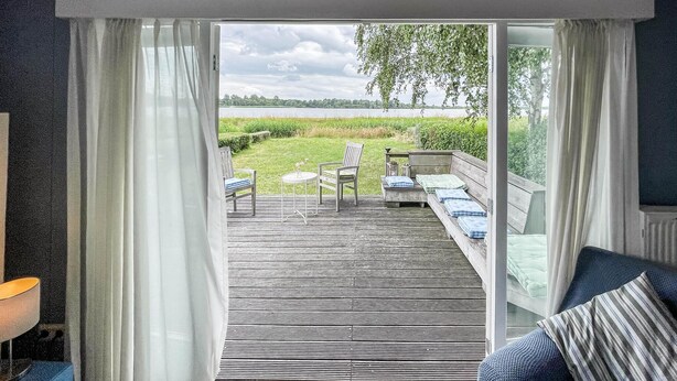 A room with a view of a grassy area and a wooden deck outside.
