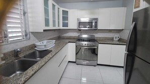 A kitchen with white cabinets, a stainless steel stove, a microwave, and a refrigerator. - Home away from home (Kingston)