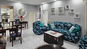 A living room with a sofa, coffee table, and dining area. - Home away from home (Kingston)