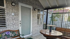 A stone-walled porch with a bench, a table, and a door. - Home away from home (Kingston)