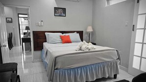 A hotel room with a bed, a bedside table, a lamp, and a window. - Home away from home (Kingston)