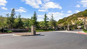 Ein Parkplatz mit einem Steindenkmal mit der Aufschrift "Vallecito's Ridge“, umgeben von Bäumen und einer hügeligen Landschaft.