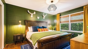 Un dormitorio con cama de madera, paredes verdes y ventana con cortinas amarillas.