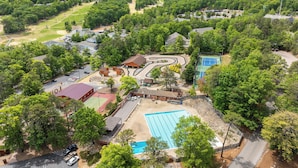 Un resort con piscina, canchas de tenis y un camino sinuoso.