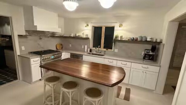 A kitchen with a central island, bar stools, white cabinets, and pendant lighting. - In-Town Lewes, Private Getaway! 4 BDRM,2.5BA. Steps to 2nd Street and Bike Trail (Lewes)