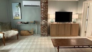 A living room with a sofa, a coffee table, a television on a wooden cabinet, and a patterned rug. - In-Town Lewes, Private Getaway! 4 BDRM,2.5BA. Steps to 2nd Street and Bike Trail (Lewes)