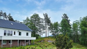 A white house with a dark roof, surrounded by a grassy landscape and tall trees. - 7 bedroom amazing home in Nedre Vats (Nedre Vats)