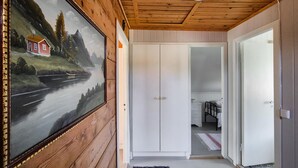 Un couloir aux murs lambrissés, une porte blanche et un tableau représentant un paysage.