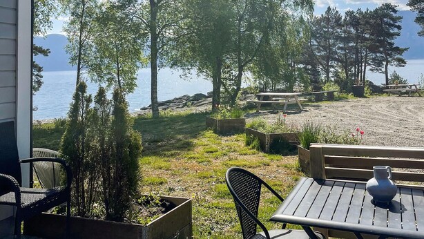 A patio with a view of a lake, wooden furniture, and planters.