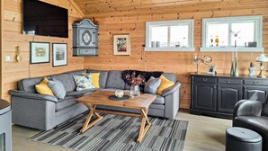 A cozy cabin interior with a grey sofa, wooden coffee table, and a black cabinet. - Cozy home in Florø with WiFi (Florø)
