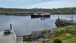 A boat docked at a pier with a rocky shoreline and a mountain in the background. - Cozy home in Florø with WiFi (Florø)