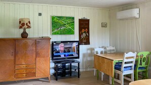 A room with a wooden cabinet, a television, a dining table with chairs, and a wall-mounted air conditioner. - Stunning home in Eidsvåg i Romsdal (Eidsvåg i Romsdal)