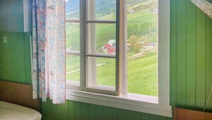 Ein Zimmer mit einem großen Fenster mit Blick auf eine grüne Landschaft und eine rote Scheune.